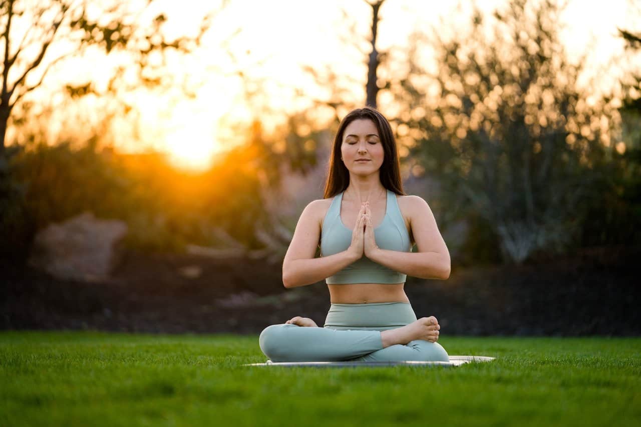 A woman sits in a yoga pose on grass at Juniper Preserve A woman sits in a yoga pose on grass at Juniper Preserve