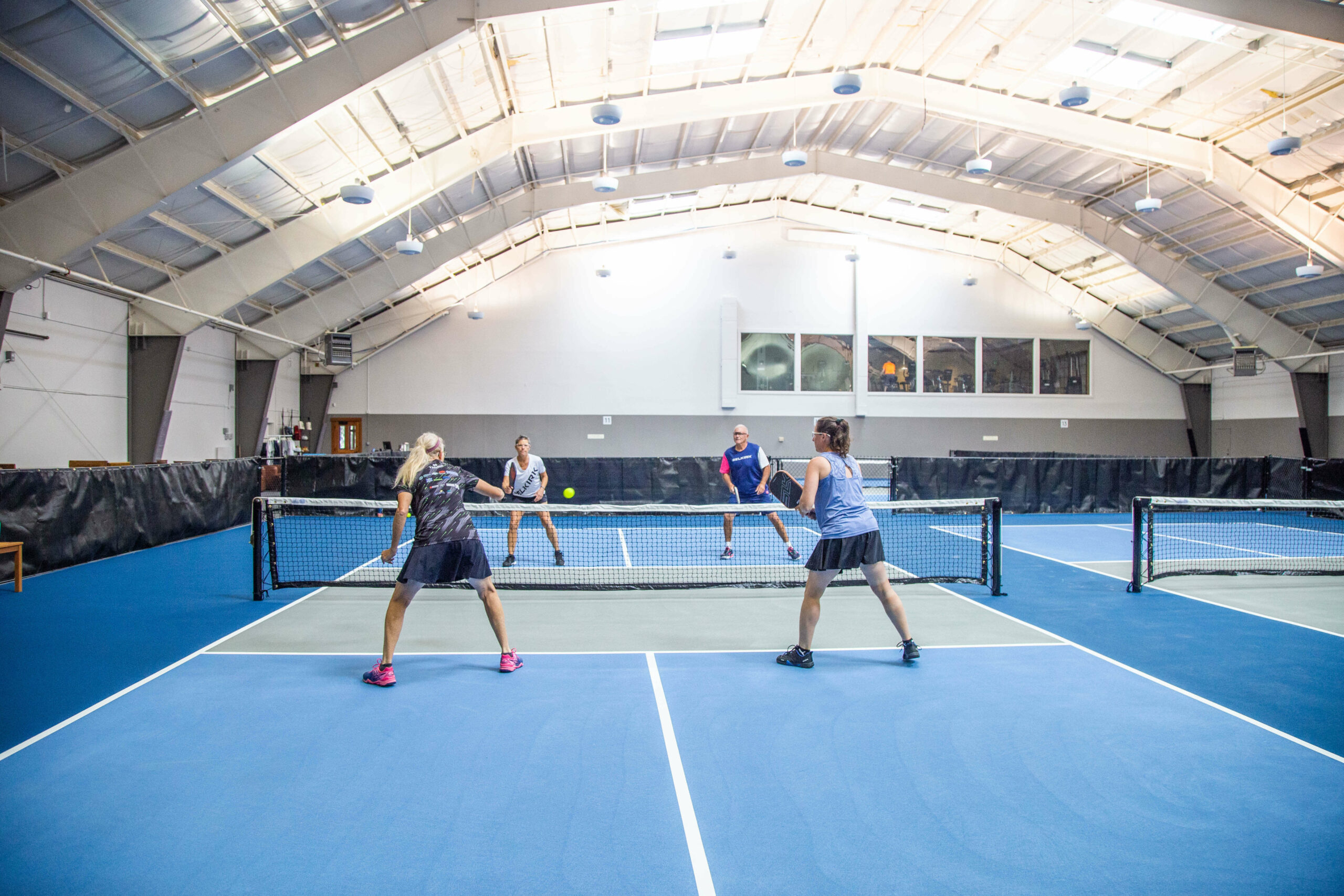 Two couples playing pickleball at indoor courts at Sage Springs. Two couples playing pickleball at indoor courts at Sage Springs.