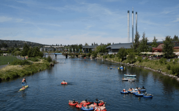 People float in tubes and on paddleboards on the Deschutes River through the Old Mill District in Bend, Oregon.